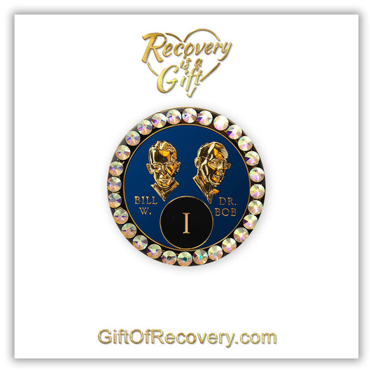 1 year AA Bill & Bob Big Book Blue recovery medallion with 28 genuine Aurora Borealis crystals around the rim, this medallion is to honor our founders and our time, stylized busts of Bill W. and Dr. Bob, with their names, are embossed 14k gold-plated brass, the medallion is sealed with resin for a glossy finish. seen on a white 3x3 card with recovery is a gift going through an open heart at the top and giftofrecovery.com on the bottom, both in the color gold.