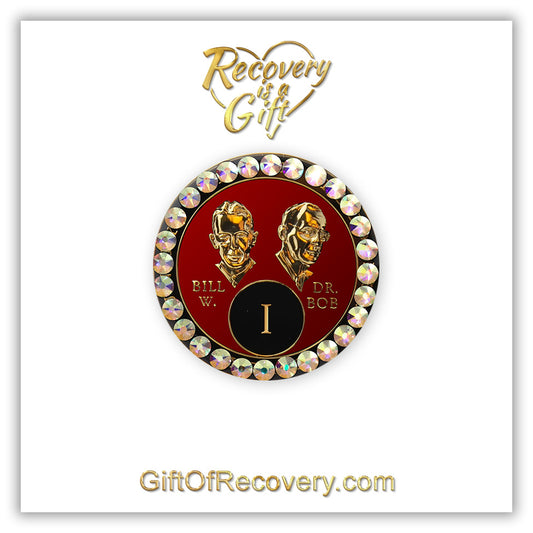 1 year AA Bill & Bob Ruby red recovery medallion with 28 genuine Aurora Borealis crystals around the rim, this medallion is to honor our founders and our time,  stylized busts of Bill W. and Dr. Bob, with their names, in embossed 14k gold-plated brass, the medallion is sealed with resin for a glossy finish, seen on a white 3x3 card with recovery is a gift going through an open heart at the top and giftofrecovery.com on the bottom, both in the color gold.
