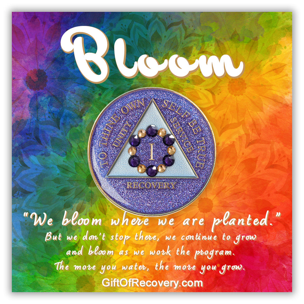 1 year AA medallion purple glitter Amethyst with 6 gold and 6 purple genuine crystals that form a circle to represent blooming through the 12 steps of recovery, around the roman numeral, to thine own self be true, unity, service, recovery embossed with 14k gold-plated brass, triangle is pearl white, sealed with resin for a shiny finish, featured on a tie-dye 3x3 card with silhouettes of flowers, bloom and description paragraph in white.