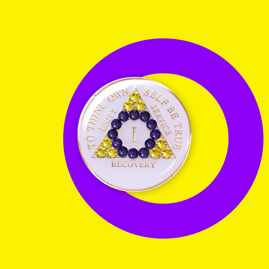 1 year AA medallion pearl white with 21 genuine crystals that form the triangle and are in the color of the intersex flag, colors are yellow and purple, to represent pride and sobriety, the AA slogan and three legacies are embossed with 14k gold-plated brass and sealed with resin for a glossy finish that will last and is scratch proof, pictured on an image of the Intersex flag colors.