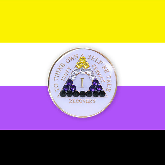 1 year AA medallion pearl white with 21 genuine crystals that form the triangle and are in the color of the Nonbinary flag, to represent pride and sobriety, the AA slogan and three legacies are embossed with 14k gold-plated brass and sealed with resin for a glossy finish that will last and is scratch proof, pictured on an image of the Nonbinary flag colors.
