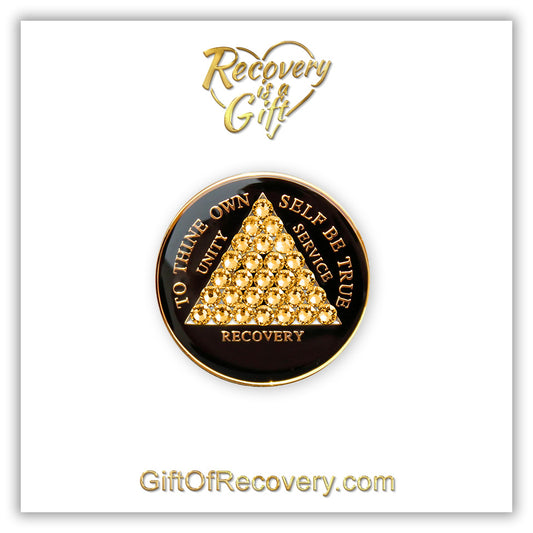 AA medallion black Onyx with 28 gold CZ genuine crystals that form the triangle entirely, this is the timeless recovery medallion, shine on with this beauty, we all have one day at a time, the AA slogan and three legacies are embossed with 14k gold-plated brass and sealed with resin for a glossy finish that will last and is scratch proof, pictured on a white 3x3 card with recovery is a gift going through an open heart at the top and giftofrecovery.com at the bottom, both in the color gold.