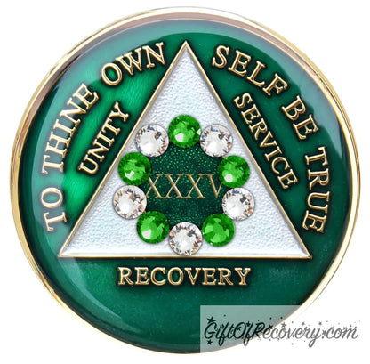 35 year emerald green AA medallion with the 10th step in emphasis in the center, 5 emerald green genuine crystals and 5 clear genuine crystals, inside the triangle is pearl white, while the circle is sparkle green. To thine own self be true, unity, service, recovery, and the roman numeral 1, are 14k gold and sealed with resin for a glossy finish.