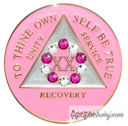20 year princess pink AA medallion with a pearl white triangle center and pink circle, surrounding the roman numeral 20 are 10 genuine crystals, 5 dark pink and 5 clear, perfect for your favorite sober princess, to thine own self be true, unity, service, recovery, the rim of the medallion, the raised triangle outline, and the roman numeral year, are in 14k gold, sealed with resin for a glossy finish.