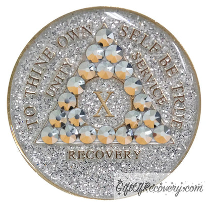 10 year silver glitter AA medallion with 21 genuine comet crystals, forming a triangle around the 1 year, while the year, unity, service, recovery, rim, and To Thine Own Self Be True are embossed in 14k gold, sealed with resin to give it a glossy finish, hand painted and scratch resistant.