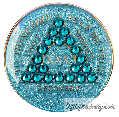 25 year AA medallion in aqua glitter with to thine own self be true, unity, service, recovery, the roman numeral in the center, and the outer rim of the medallion embossed in 14k gold plated brass, the center triangle has 21 genuine blue zircon crystal to give it a sparkle, it is sealed with resin for a shiny finish.