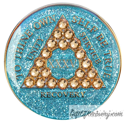 35 year Aqua glitter AA medallion with 21 gold genuine crystal making a triangle in the center, and to thine own self be true, unity, service, recovery, the roman numeral in the center and the rim of the recovery medallion embossed in 14k gold plated brass and sealed with resin for a glossy shine.