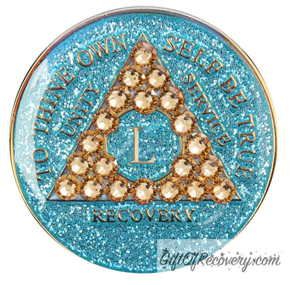 50 year Aqua glitter AA medallion with 21 gold genuine crystal making a triangle in the center, and to thine own self be true, unity, service, recovery, the roman numeral in the center and the rim of the recovery medallion embossed in 14k gold plated brass and sealed with resin for a glossy shine.