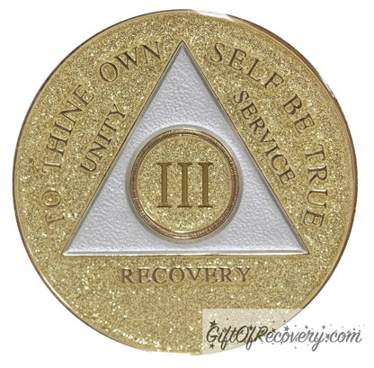 3 year AA medallion Gold glitter, with the triangle pearl white and to thine own self be true, unity, service, recovery, and the roman numeral embossed with 14k gold-plated brass, the recovery medallion is sealed with resin for a shiny finish that will last and is scratch proof.
