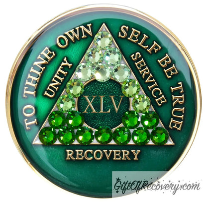 45 year AA medallion, emerald green with 21 genuine green crystals ranging from light to dark green in the shape of the triangle in the center to emphasize the transformation in the recovery journey, to thine own self be true, roman number, unity, service recovery are embossed in 14k gold-plated brass, the middle circle is sparkle green and the recovery medallion is sealed in resin for a shiny finish that lasts.