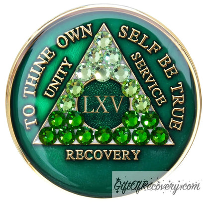 65 year AA medallion, emerald green with 21 genuine green crystals ranging from light to dark green in the shape of the triangle in the center to emphasize the transformation in the recovery journey, to thine own self be true, roman number, unity, service recovery are embossed in 14k gold-plated brass, the middle circle is sparkle green and the recovery medallion is sealed in resin for a shiny finish that lasts.