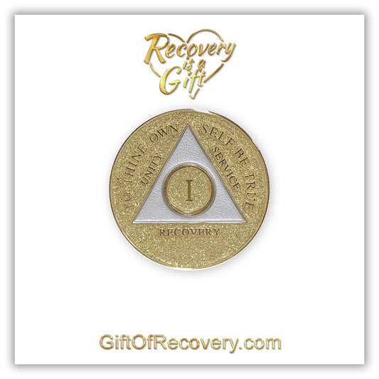 1 year AA medallion Gold glitter, with the triangle pearl white and to thine own self be true, unity, service, recovery, and the roman numeral embossed with 14k gold-plated brass, the recovery medallion is sealed with resin for a shiny finish that will last and is scratch proof, the medallion is featured on a white 3x3 card with recovery is a gift going through a heart in the center top and giftofrecovery.com at the bottom center, both are in the color gold. 
