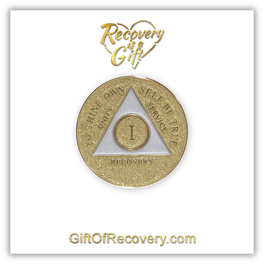 1 year AA medallion Gold glitter, with the triangle pearl white and to thine own self be true, unity, service, recovery, and the roman numeral embossed with 14k gold-plated brass, the recovery medallion is sealed with resin for a shiny finish that will last and is scratch proof, the medallion is featured on a white 3x3 card with recovery is a gift going through a heart in the center top and giftofrecovery.com at the bottom center, both are in the color gold.