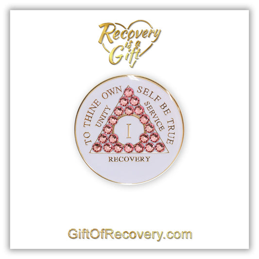 1 year pearl white AA medallion with Twenty-one genuine rose crystals in the shape of the triangle, unity, service, recovery, roman numeral, and to thine own self be true, embossed in 14k gold-plated brass and sealed with resin for a glossy finish that is scratch proof and will last, the recovery medallion is featured on a white 3x3 card with recovery is a gift in a heart at the top and giftofrecovery.com at the bottom, both are in the color gold. 