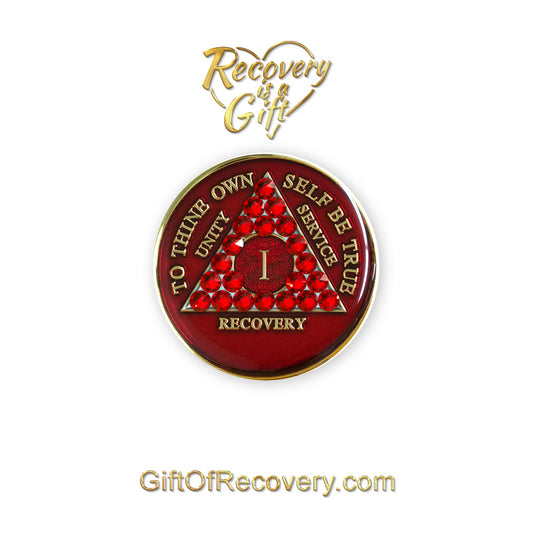 1 year AA medallion ruby red with to thine own self be true, unity, service, recovery, and roman numeral are in embossed with 14k gold-plated brass, the recovery medallion is sealed in resin for a shiny finish that will last and is scratch proof, the medallion is featured on a white 3x3 card with recovery is a gift going through a heart and giftofrecovery.com at the bottom, both are in the color gold. 