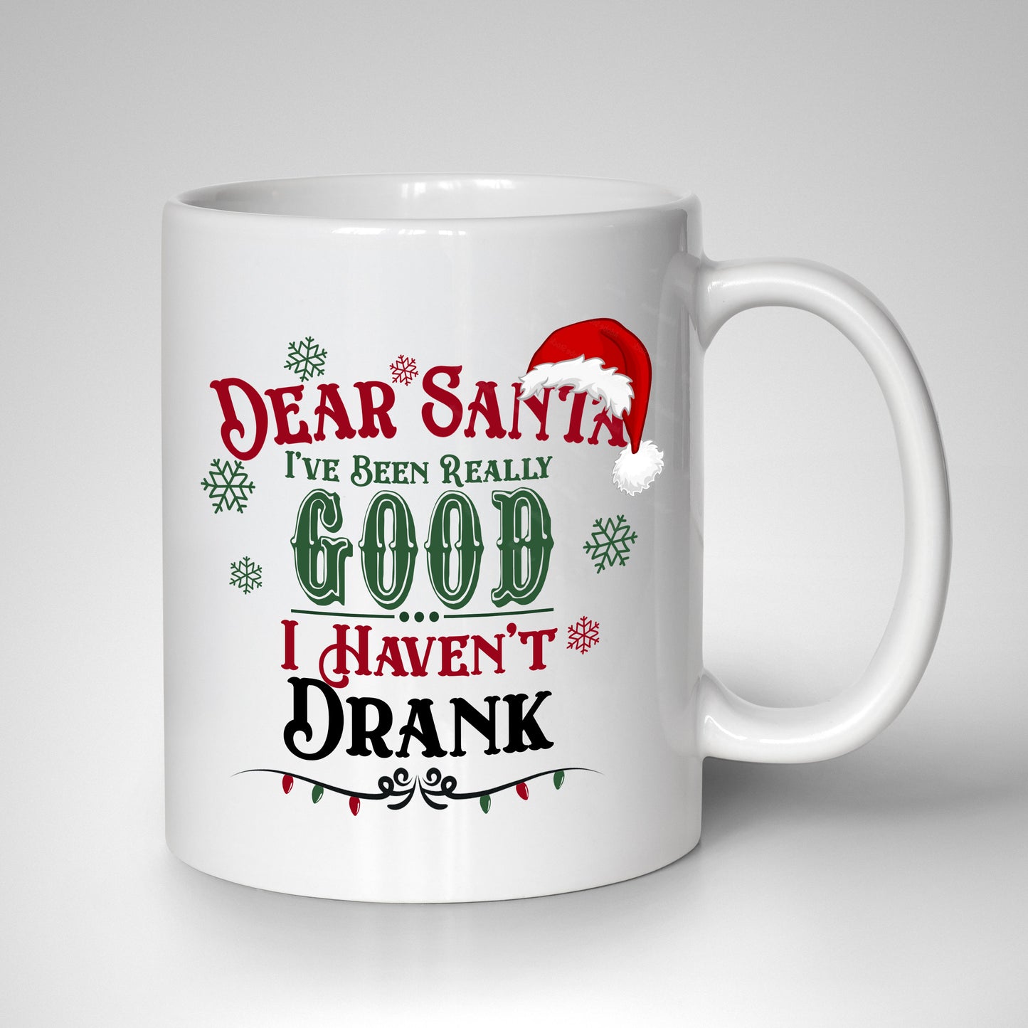 Festive lettering reading "Dear Santa, I Have Been Very Good, I Haven't Drank," with a Santa hat, snowflakes, and red and green Christmas lights on a white 15oz mug.