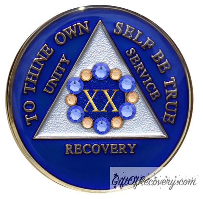 20 year AA medallion Big Book blue with 6 genuine blue crystals and 6 gold in a circle around the roman numeral like a flower symbolizing the 12 steps and growth in recovery, the triangle is pearl white, AA slogan and three legacies are embossed 14k gold-plated brass, sealed with resin for a shiny finish.