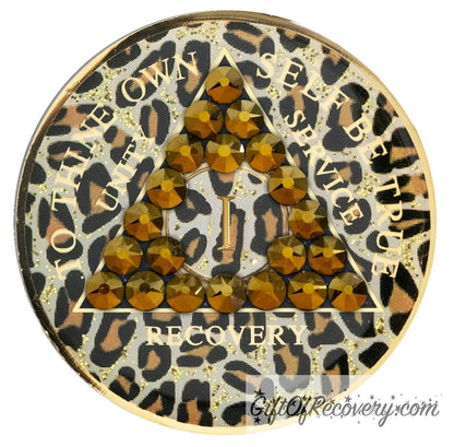 1 year AA medallion in leopard print with gold flake glitter spots and 21 genuine dorado crystals shaped in a triangle around the year, the outer rim is 14k gold and the unity, service, recovery, To thine own self be true and the year is 14k gold foil, let your sobriety shine, not your time.
