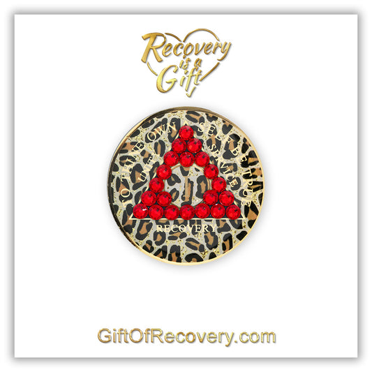 1 year AA medallion Leopard print with 21 red genuine crystals in the shape of the triangle, with to thine own self be true, unity, service, recovery, and the roman numeral in light gold foil, let your recovery shine, not your time, the medallion is sealed with resin for a shiny finish that will last and is scratch proof, the medallion is featured on a white 3x3 card with Recovery is a Gift goin through a heart at the top, in the center, and GiftOfRecovery.com at the bottom, in the color gold.